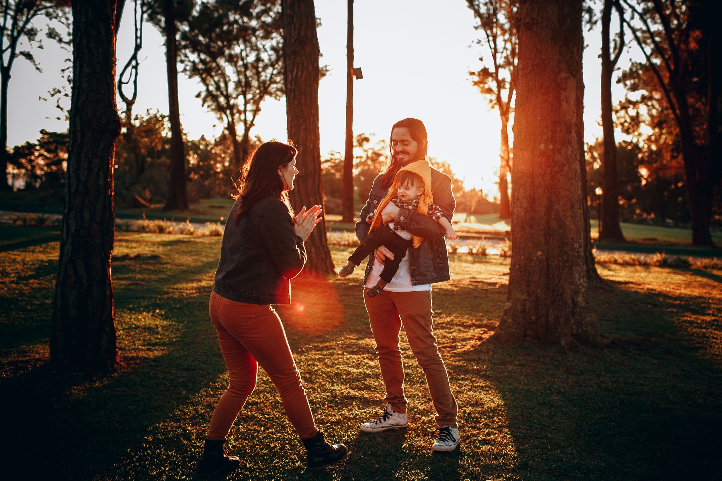 Parents sharing a playful moment with their young child in the evening sun